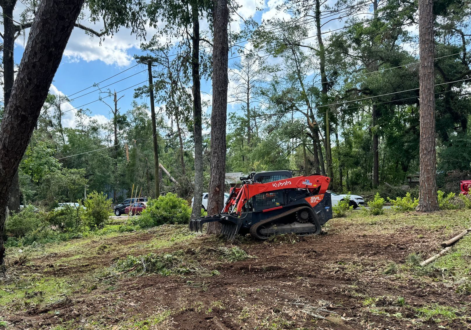A red and black tractor is sitting in the middle of a forest.