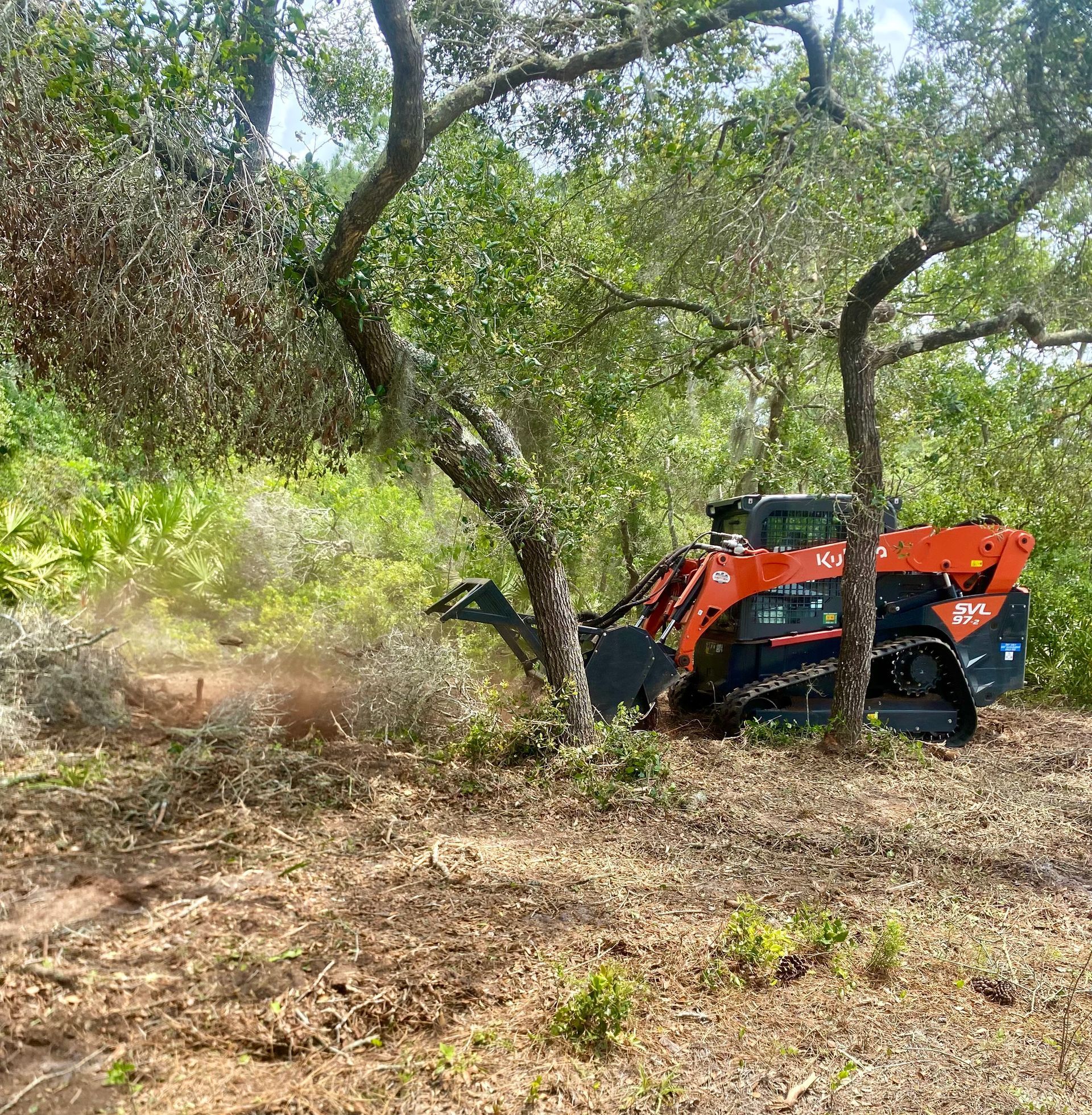 A tractor is cutting down a tree in a field.