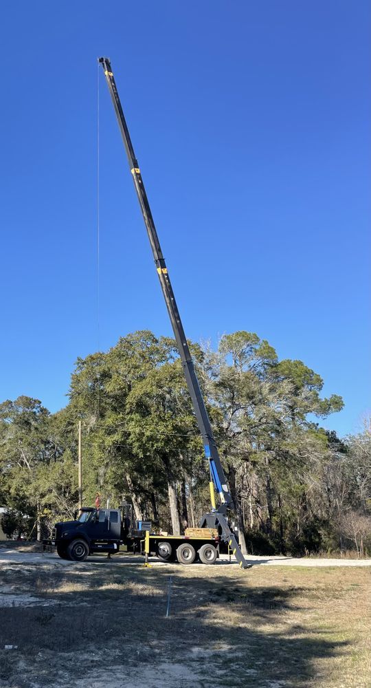 A large crane is sitting on top of a truck in a field.