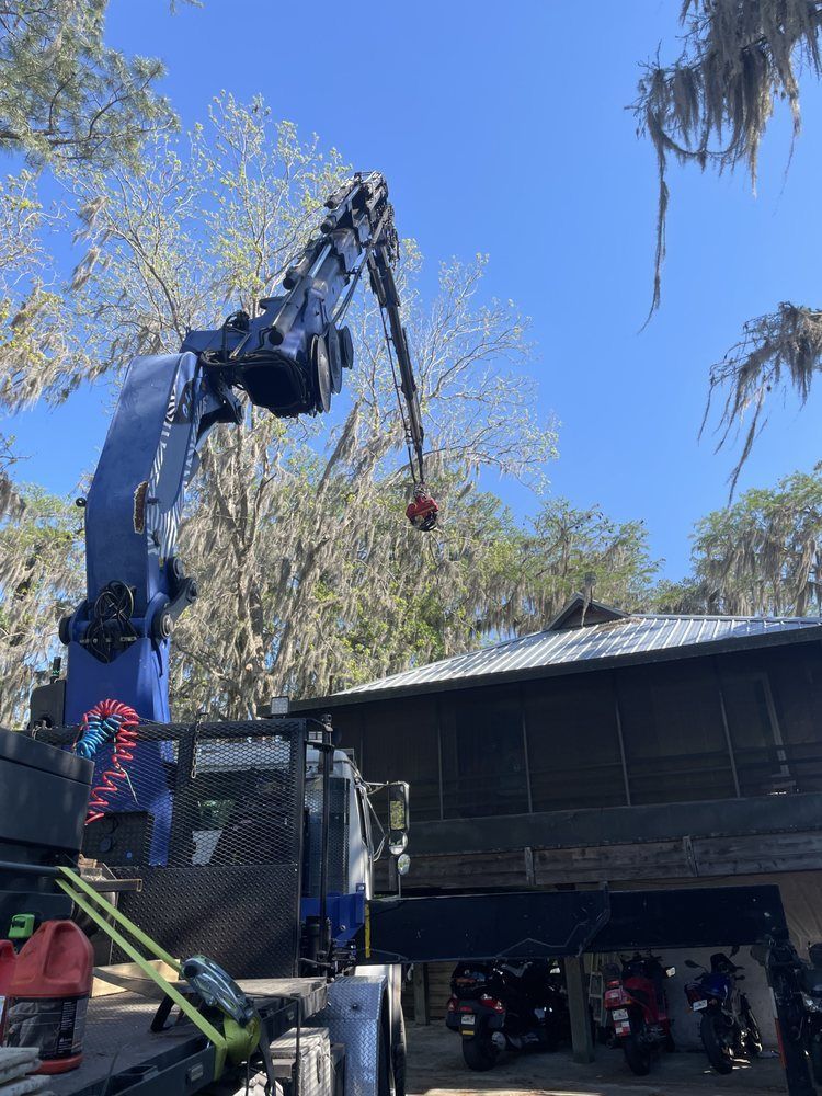A crane is lifting a tree in front of a house.