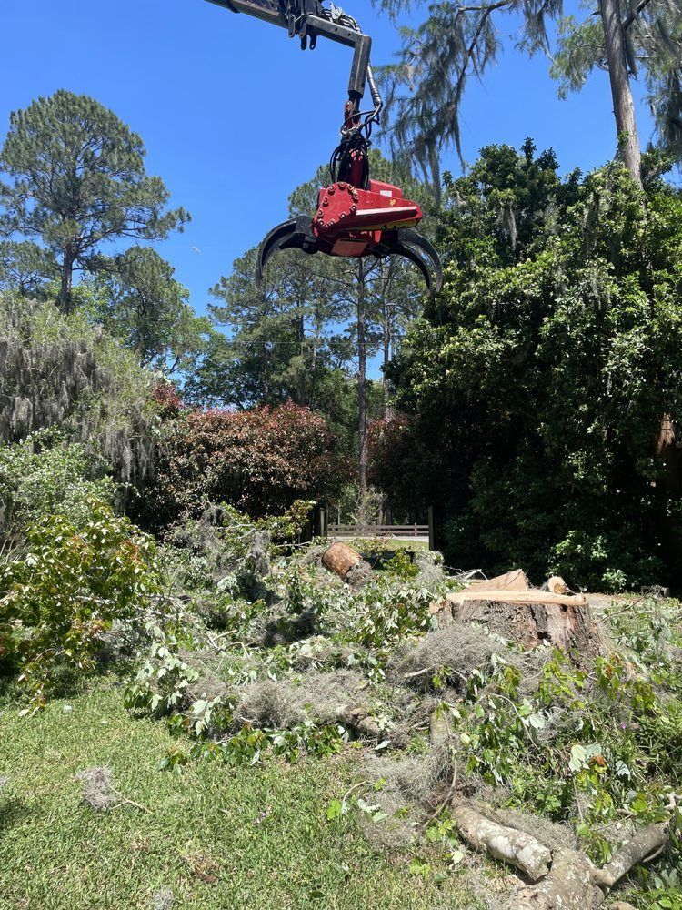 A crane is lifting a tree stump in a yard.