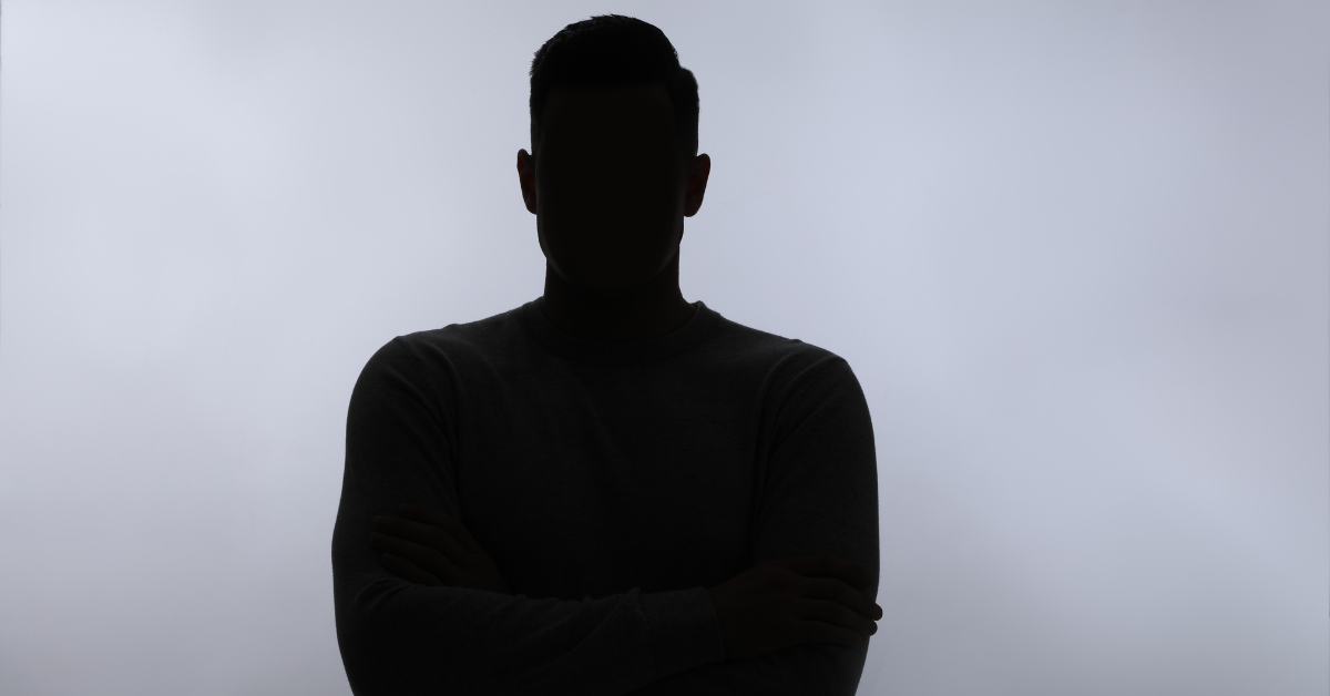 Silhouetted person with arms crossed against a bright, cloudy sky