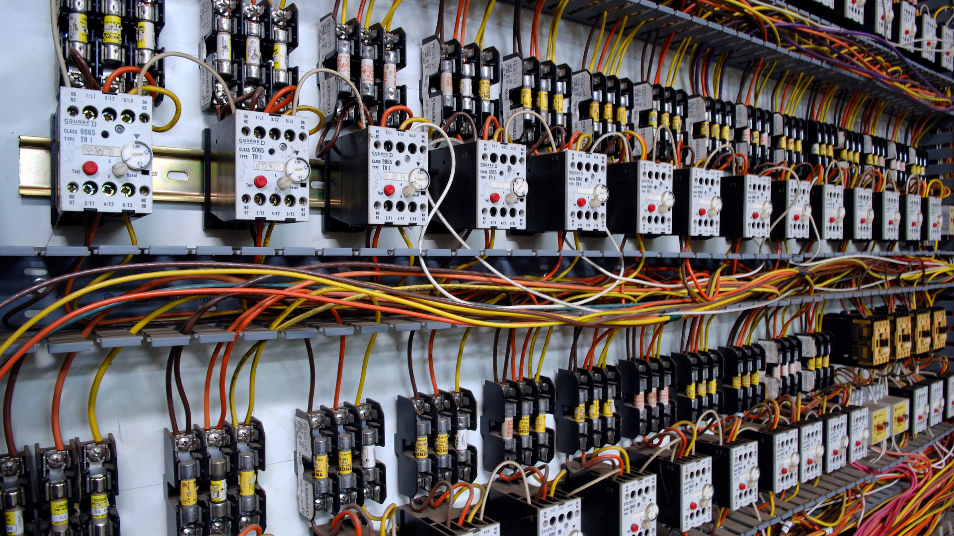 Rows of electrical control panels and wiring inside an industrial cabinet, with multicolored cables and relays.