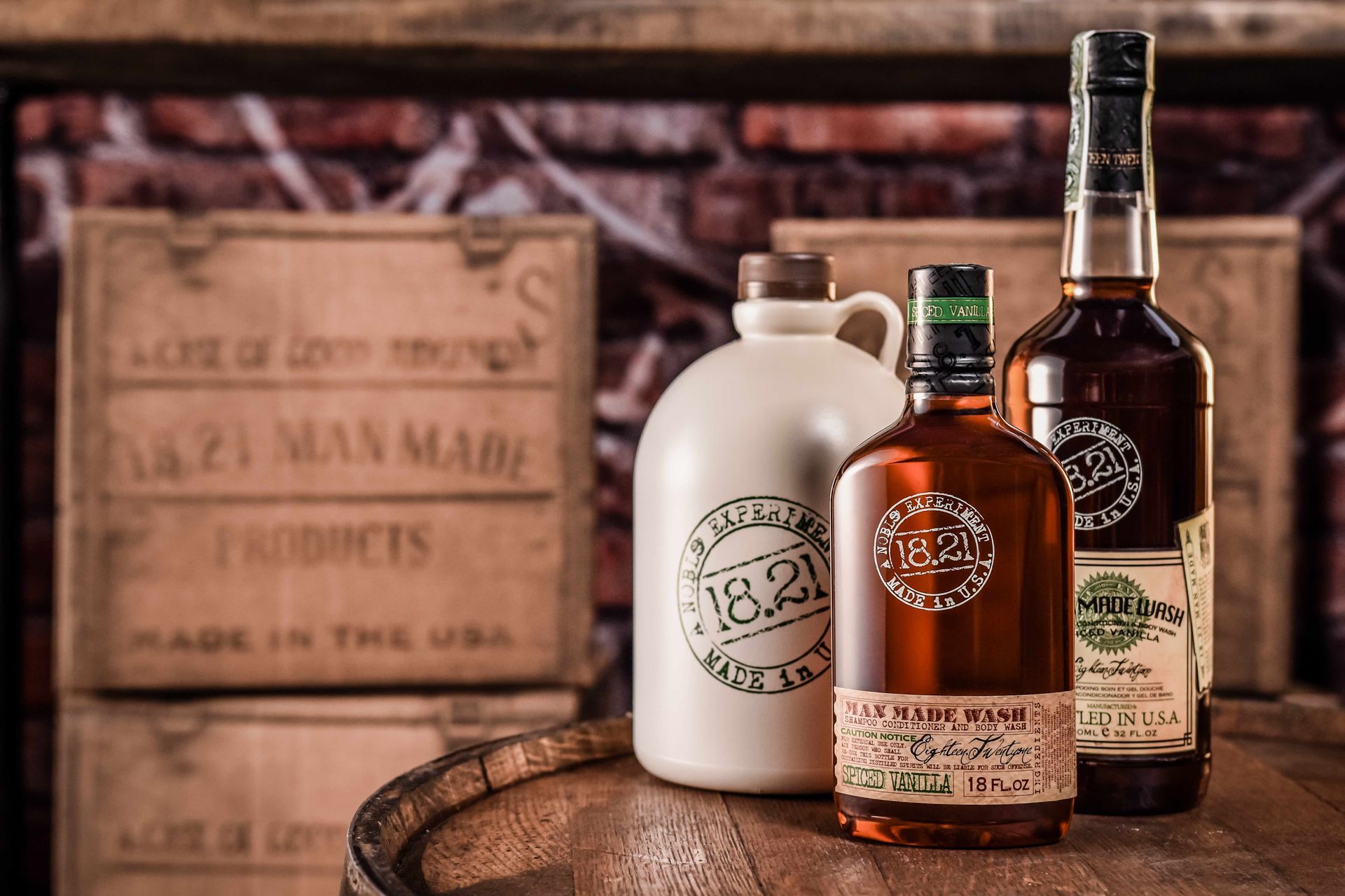 Three bottles of alcohol are sitting on top of a wooden barrel.