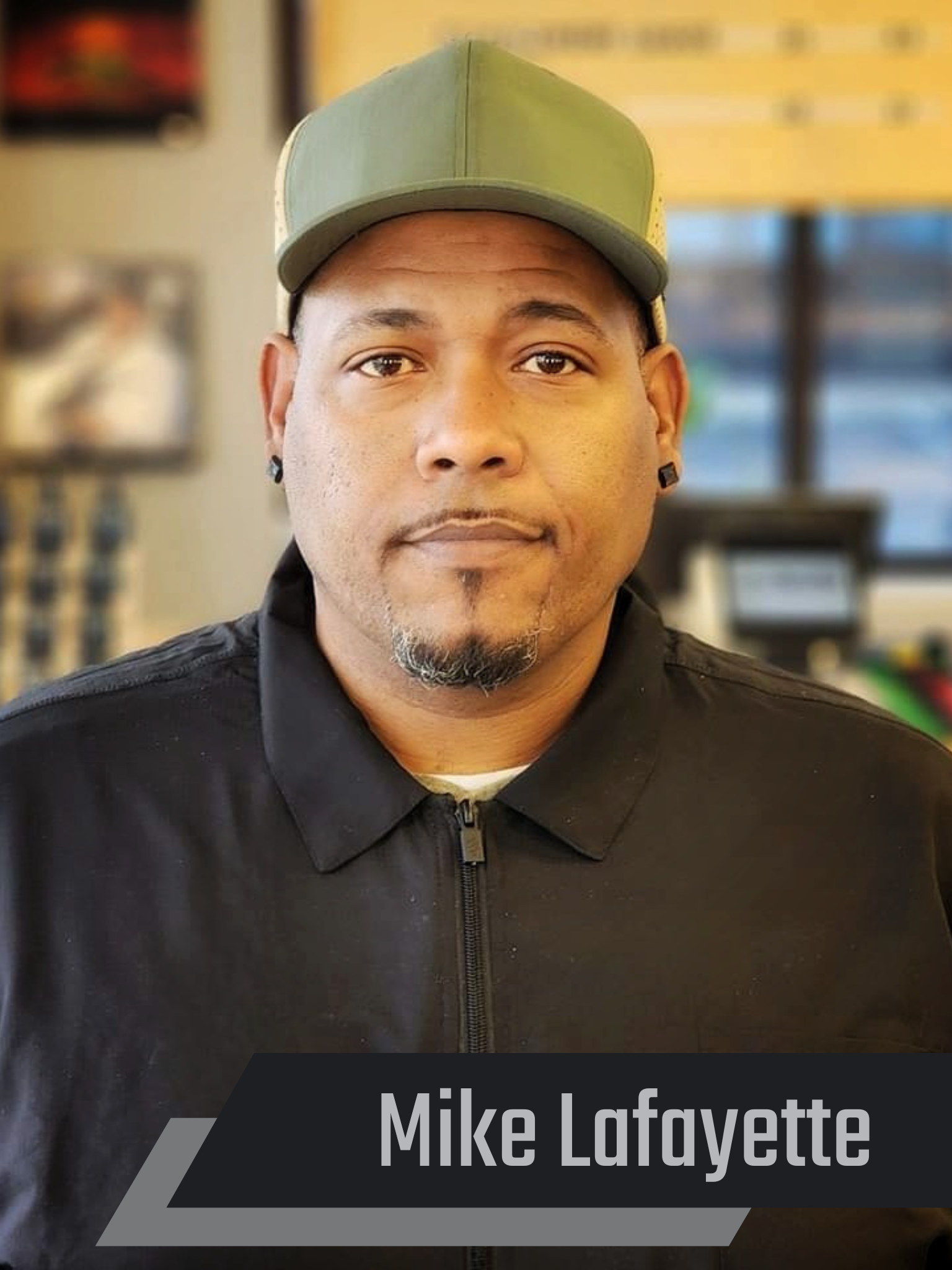 A man wearing a green hat and a black shirt is standing in a room.