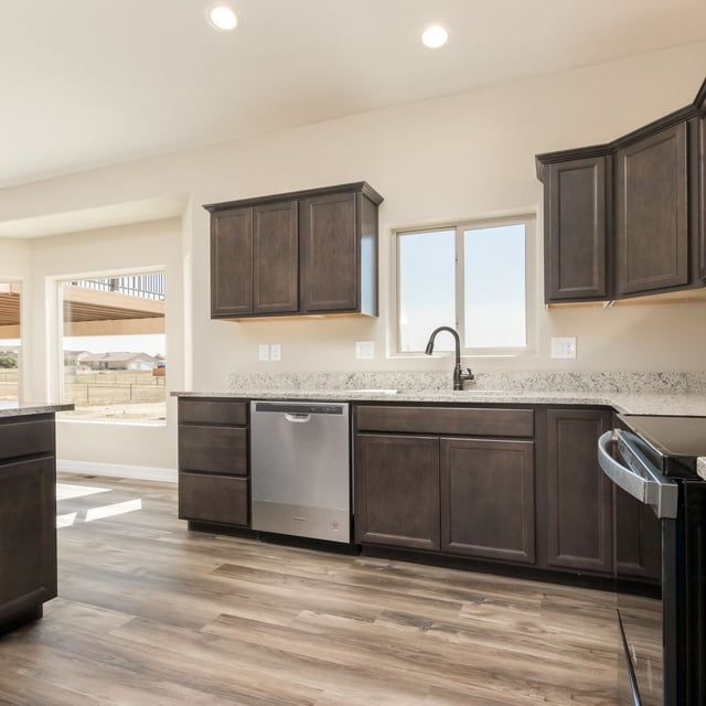 A kitchen with wooden cabinets , stainless steel appliances , a sink , and a window.