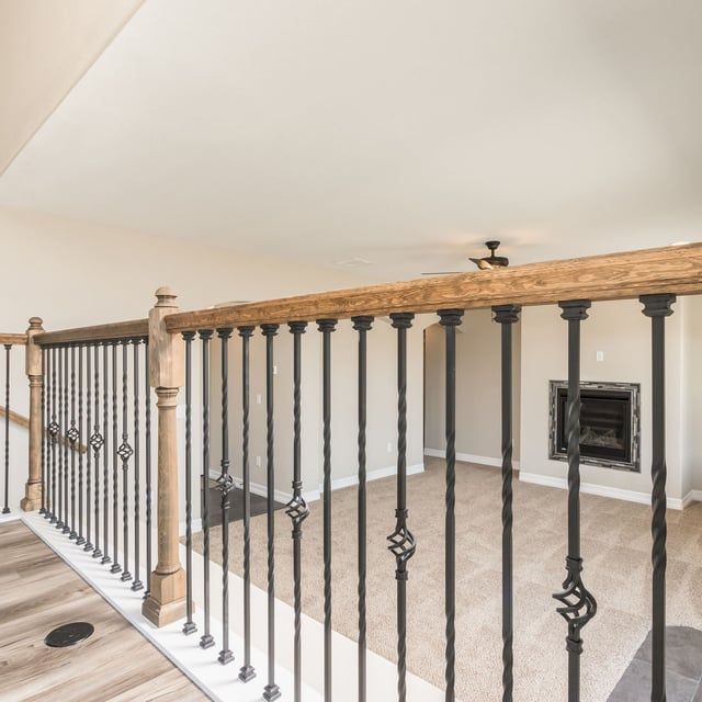 A staircase with a wrought iron railing and a wooden handrail