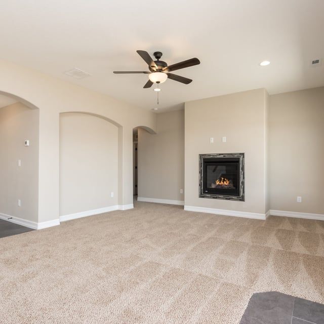 A living room with a fireplace and a ceiling fan