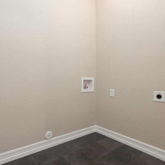 A corner of a room with tile floors and beige walls.