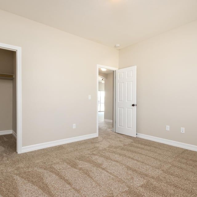 An empty bedroom with tan carpet and a white door