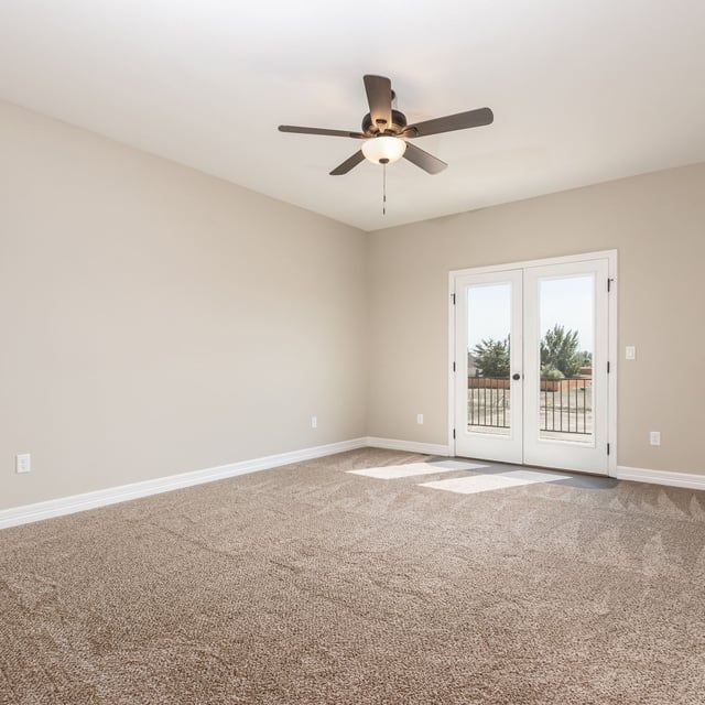 An empty room with a ceiling fan and sliding glass doors