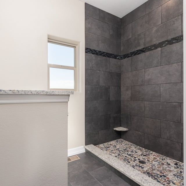 A bathroom with a walk in shower and a window