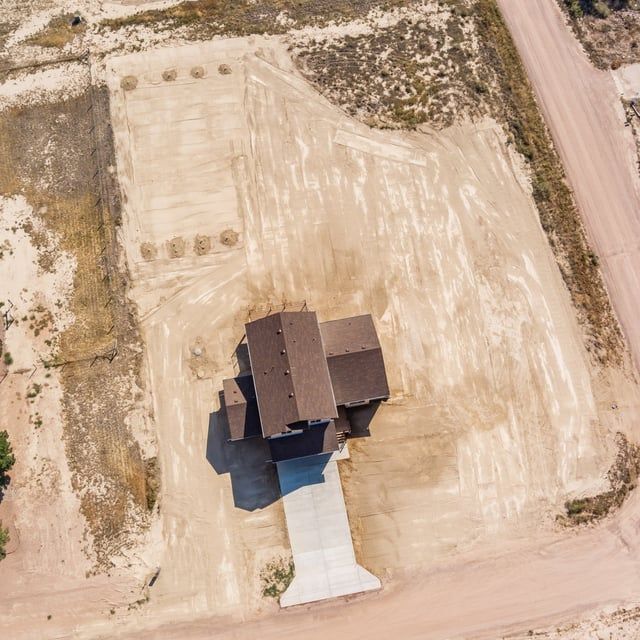 An aerial view of a house in the middle of a dirt field