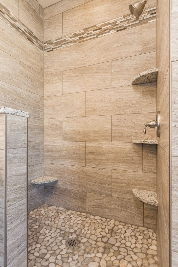 A bathroom with a walk in shower and a stone floor.