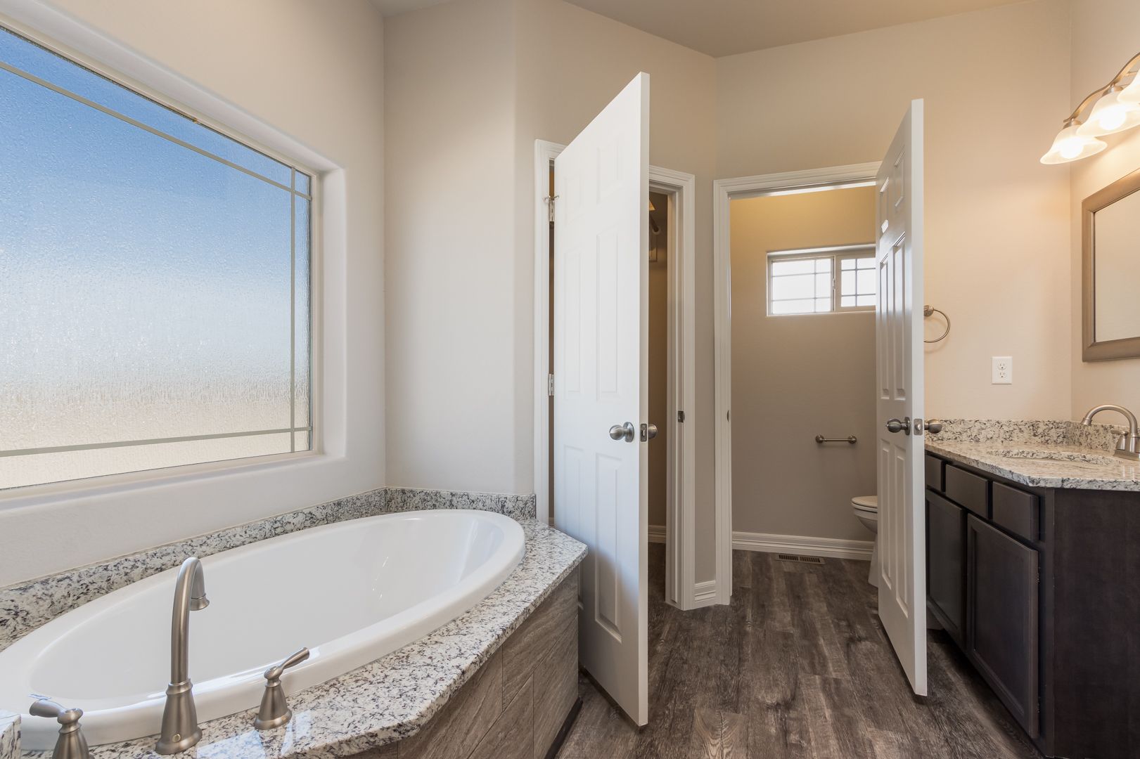 A bathroom with a tub , sink , mirror and window.