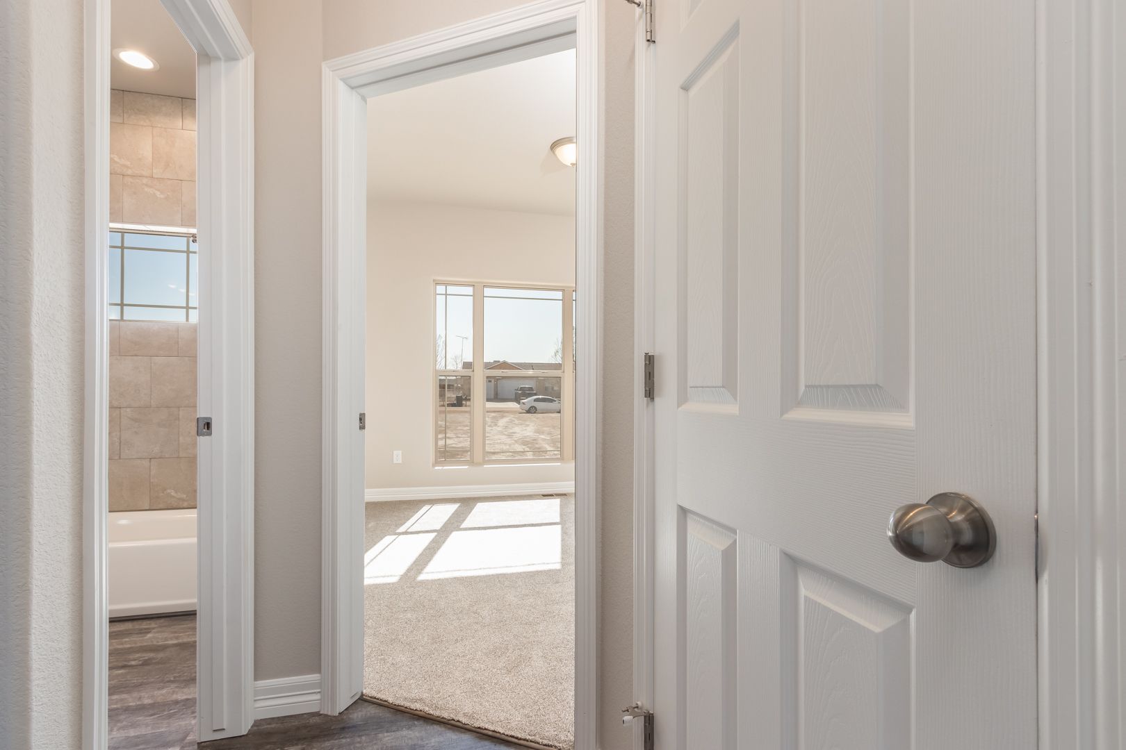 A hallway leading to a bedroom and a bathroom in a house.
