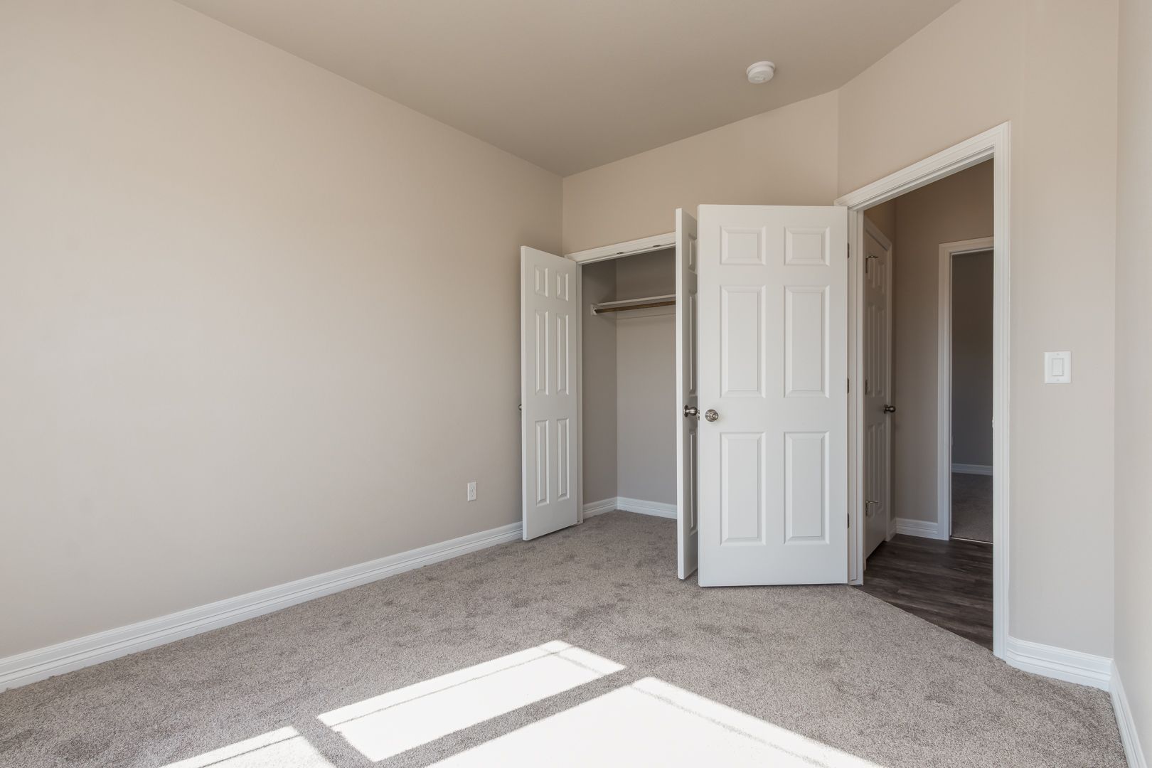 An empty bedroom with a closet and a carpeted floor.