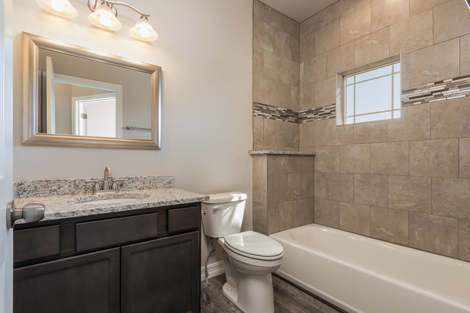 A bathroom with a toilet , sink , tub and mirror.