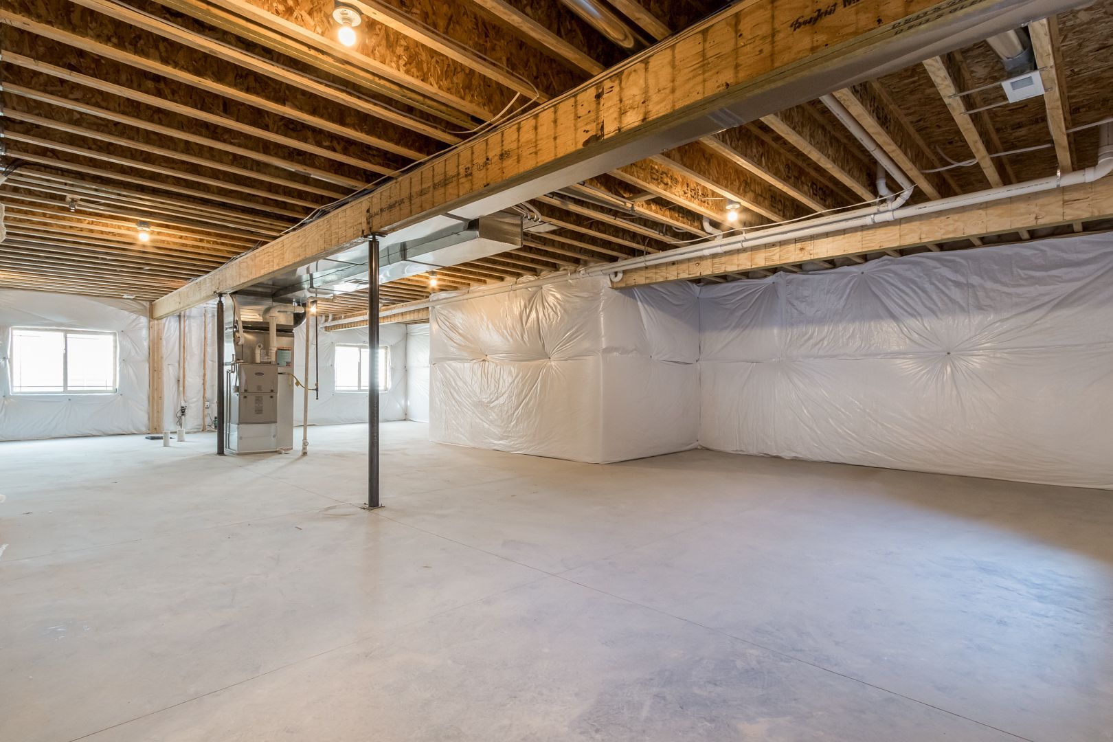 An empty basement with a wooden ceiling and white insulation.