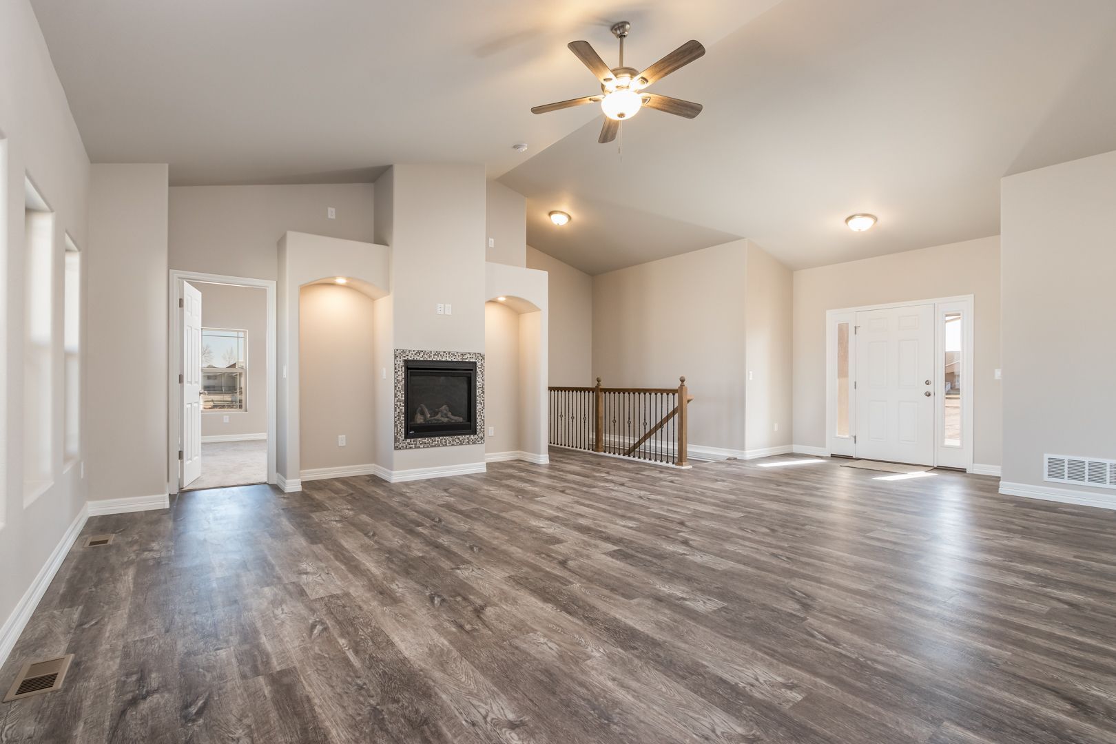 An empty living room with hardwood floors and a ceiling fan.