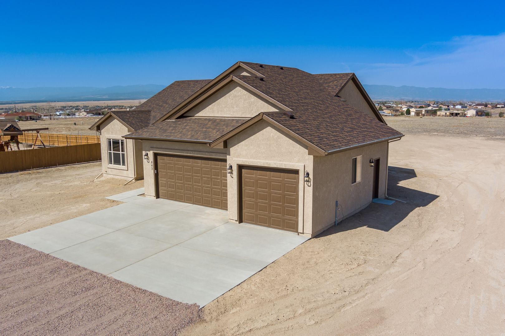 An aerial view of a house with two garages in the desert.