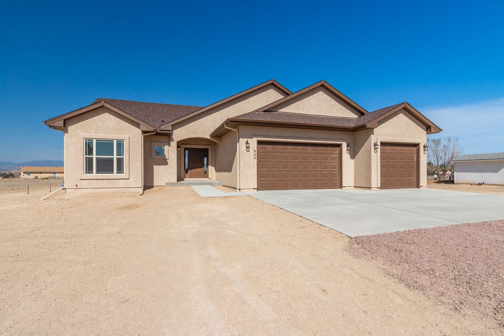 A large house with three garage doors and a concrete driveway
