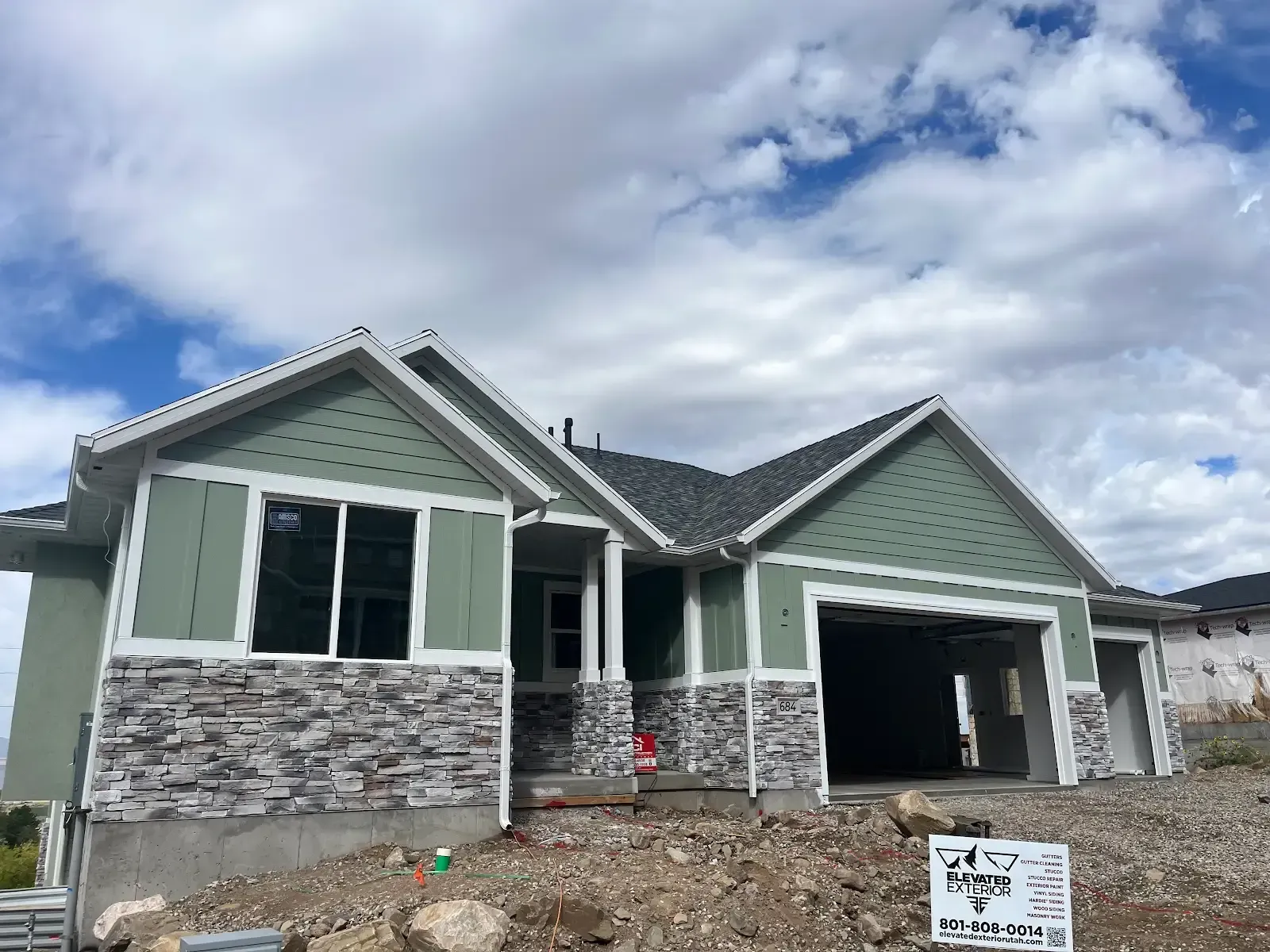 A house is being built on a hill with a sign in front of it.