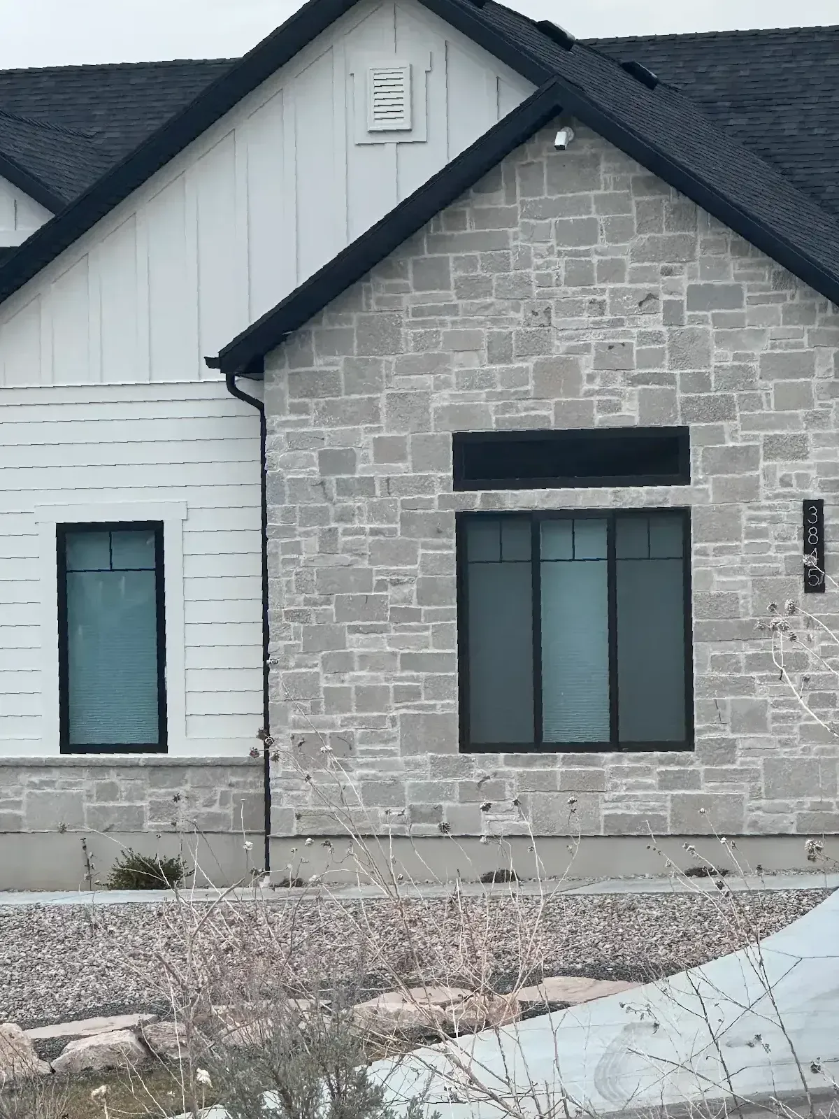 A white and stone house with a black roof