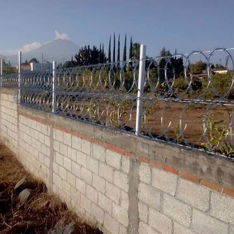 Una pared de ladrillos con alambre de púas encima.