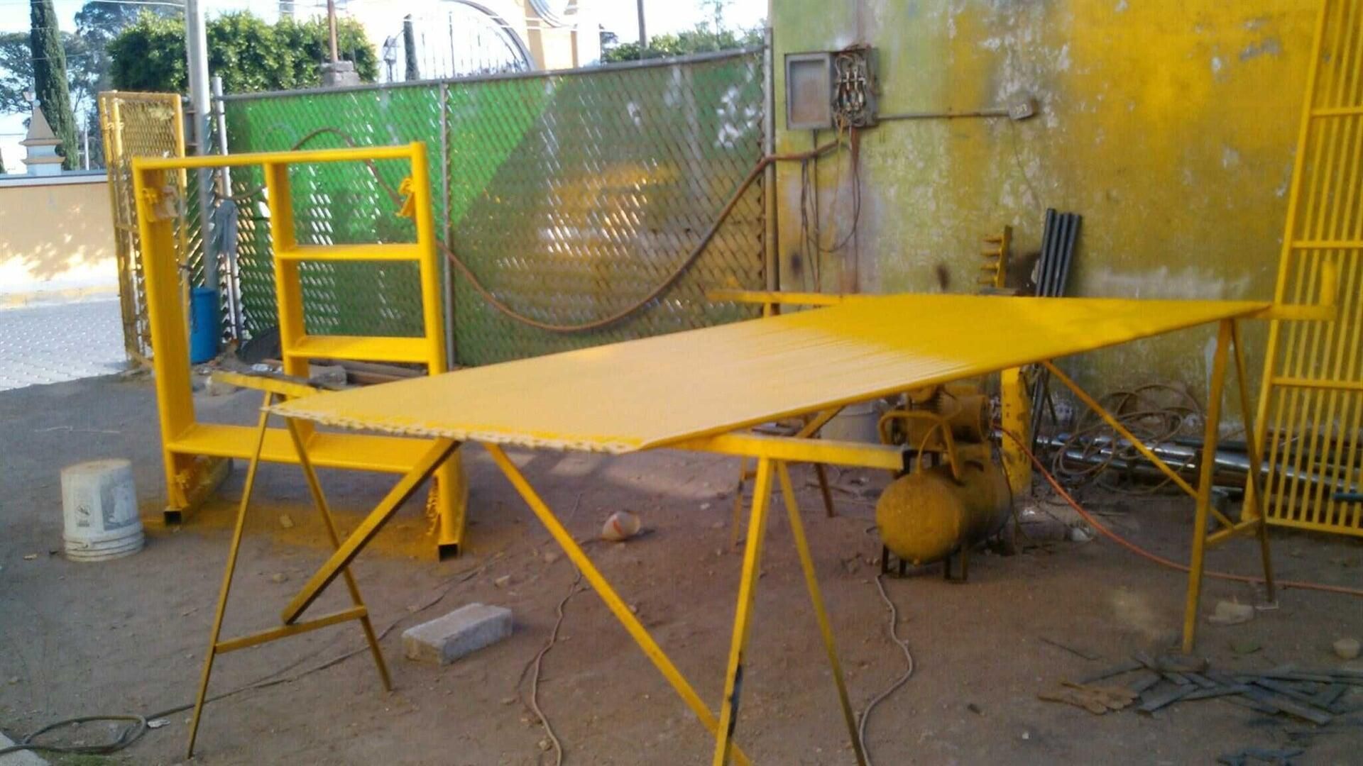 Una mesa amarilla con una valla verde al fondo