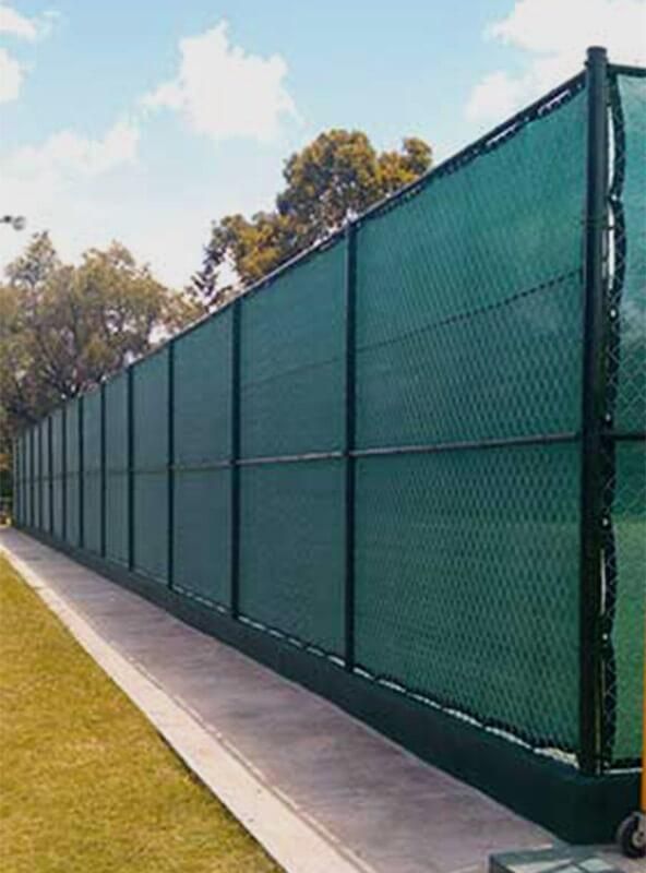 Una cancha de tenis con una valla verde que la rodea