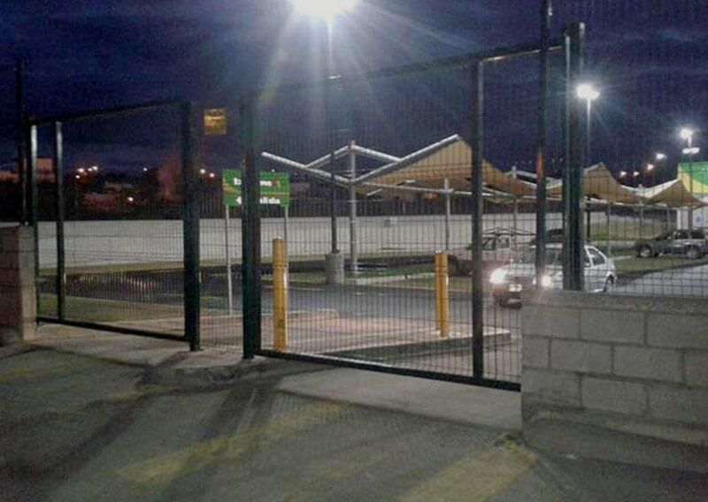 Un coche está aparcado detrás de una valla en un aparcamiento por la noche.