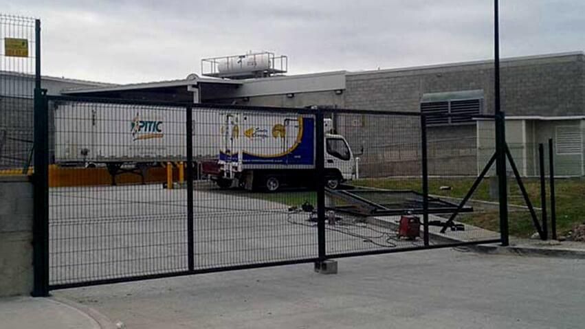 Un camión está estacionado detrás de una valla frente a un edificio.