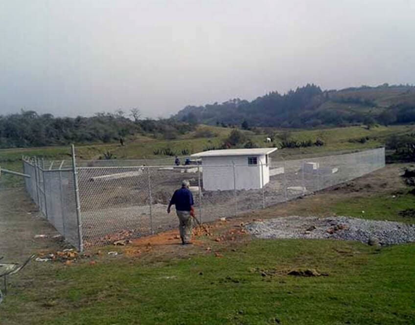 Un hombre camina por una zona vallada en un campo.