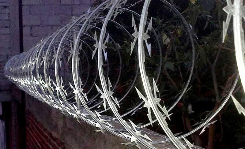 Una hilera de alambre de púas está colocada encima de una cerca.