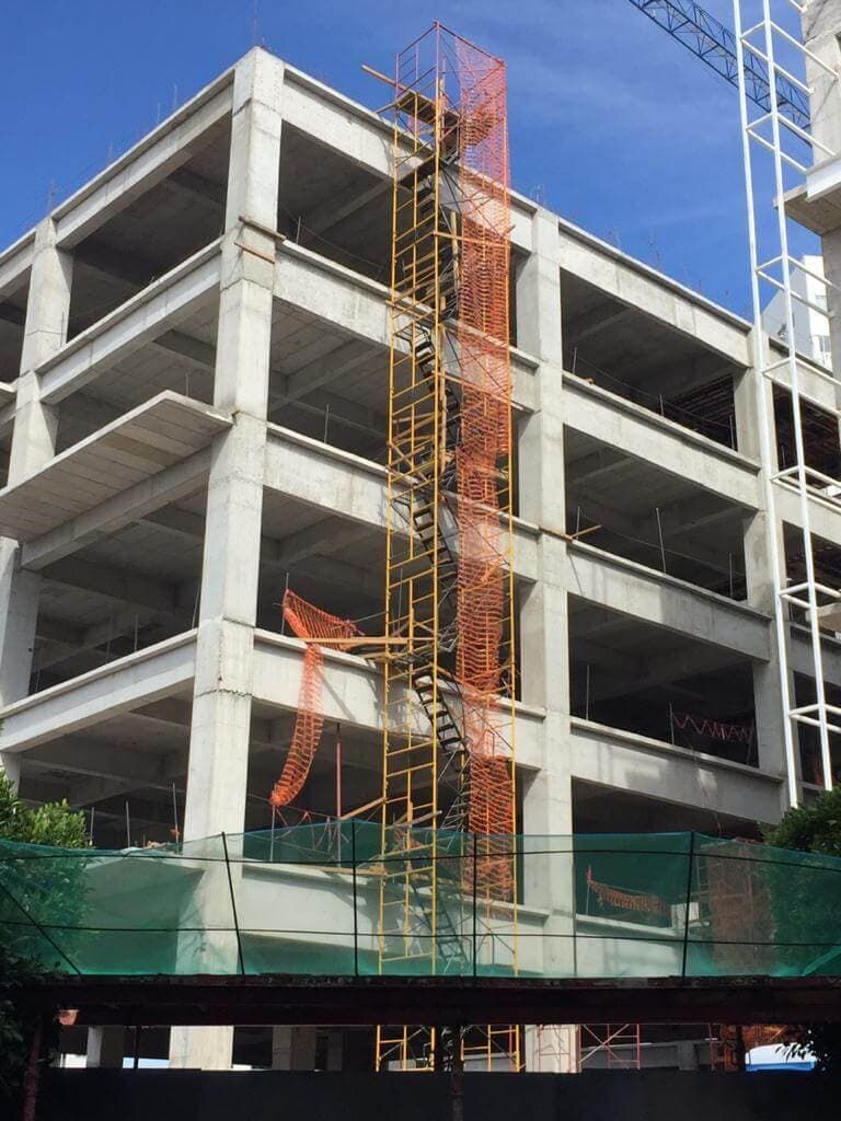 Un gran edificio en construcción con andamios y una grúa al fondo.