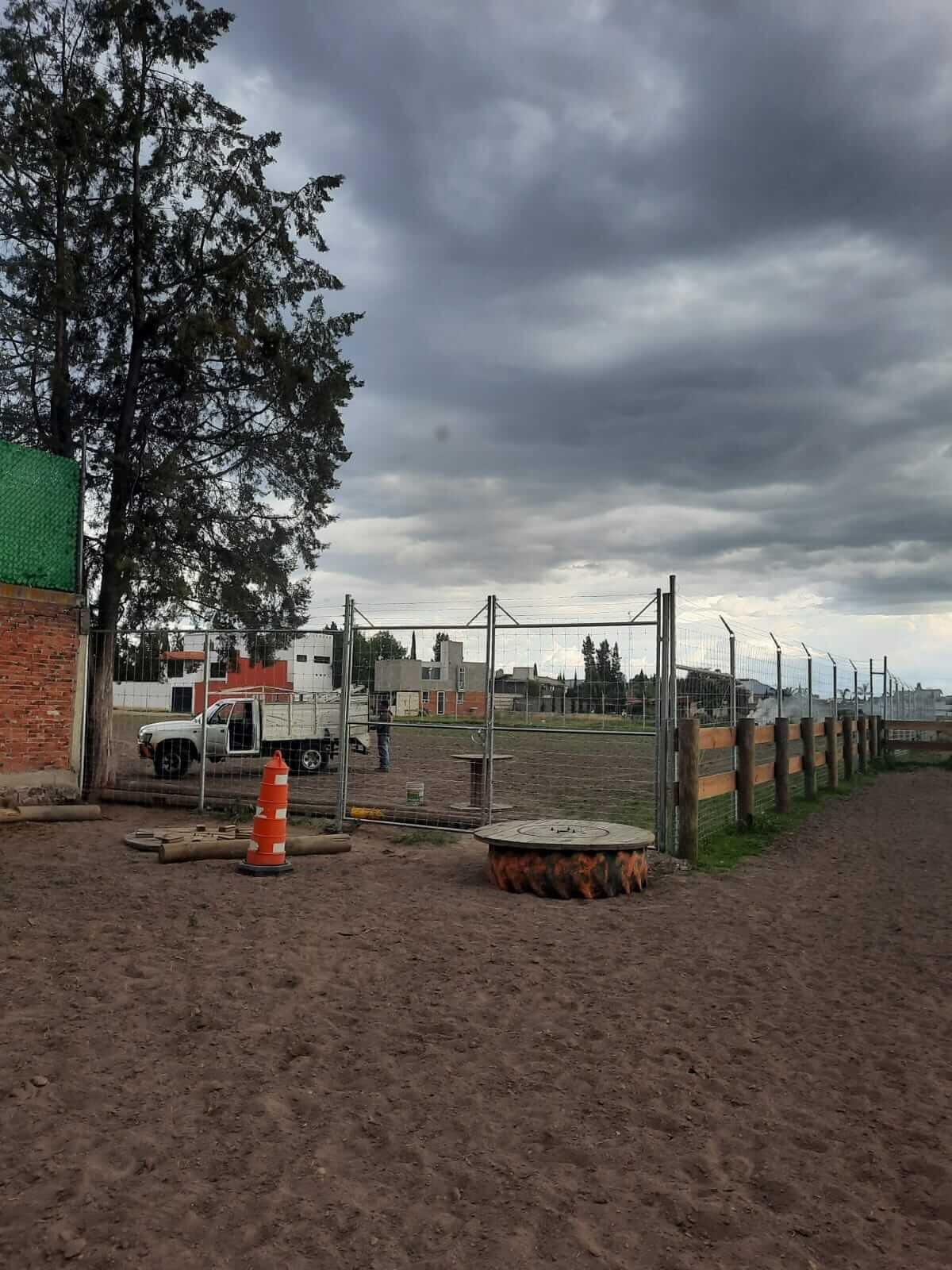 Un camión blanco está estacionado en un campo de tierra detrás de una valla.