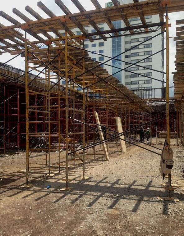 Un sitio de construcción con andamios y un edificio al fondo