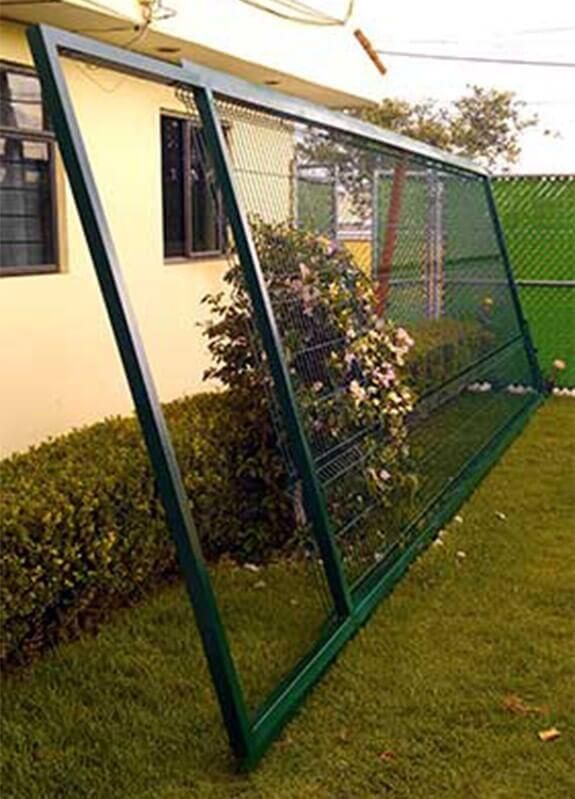 Una valla verde está sentada en el césped frente a una casa.