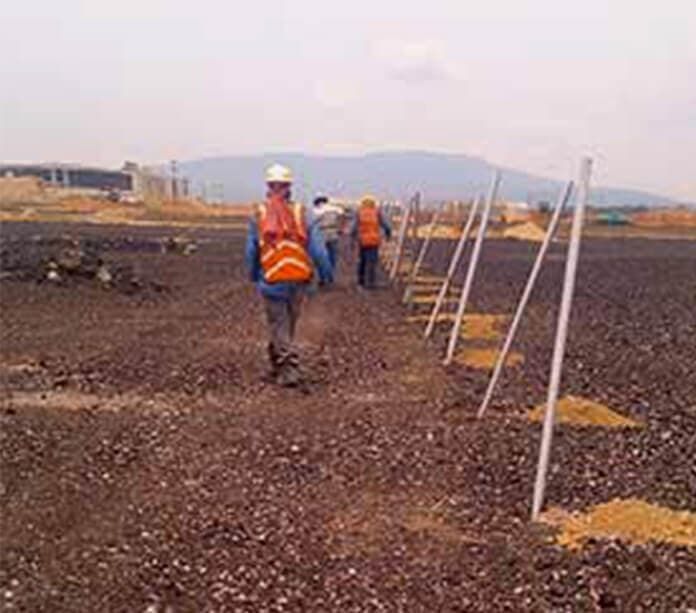 Un grupo de trabajadores de la construcción camina por un campo de tierra.
