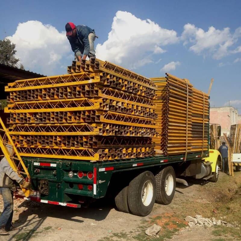 Un hombre está parado encima de una pila de andamios en la parte trasera de un camión