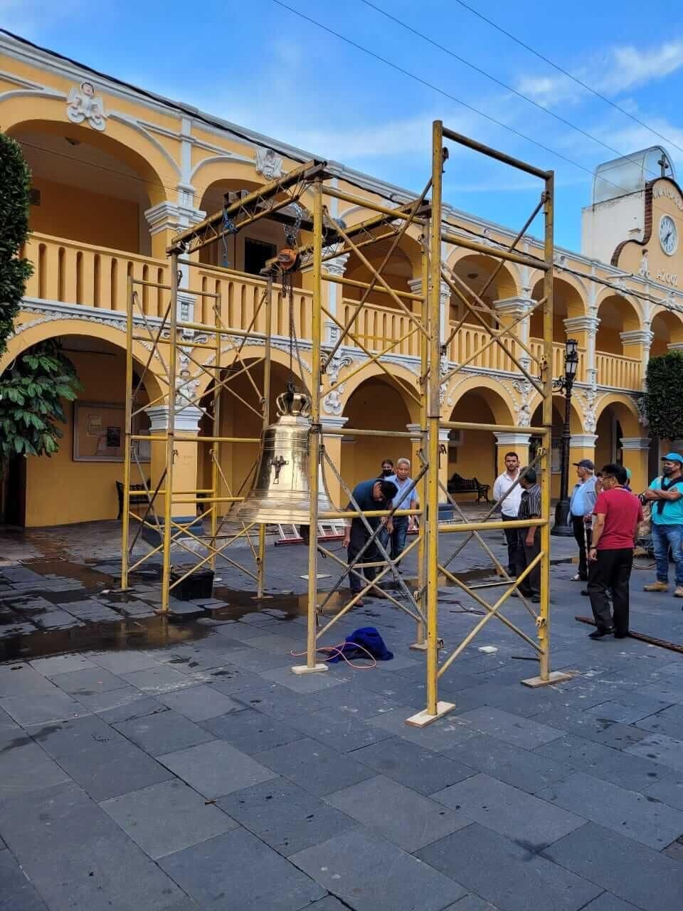 Se está instalando una gran campana frente a un edificio.