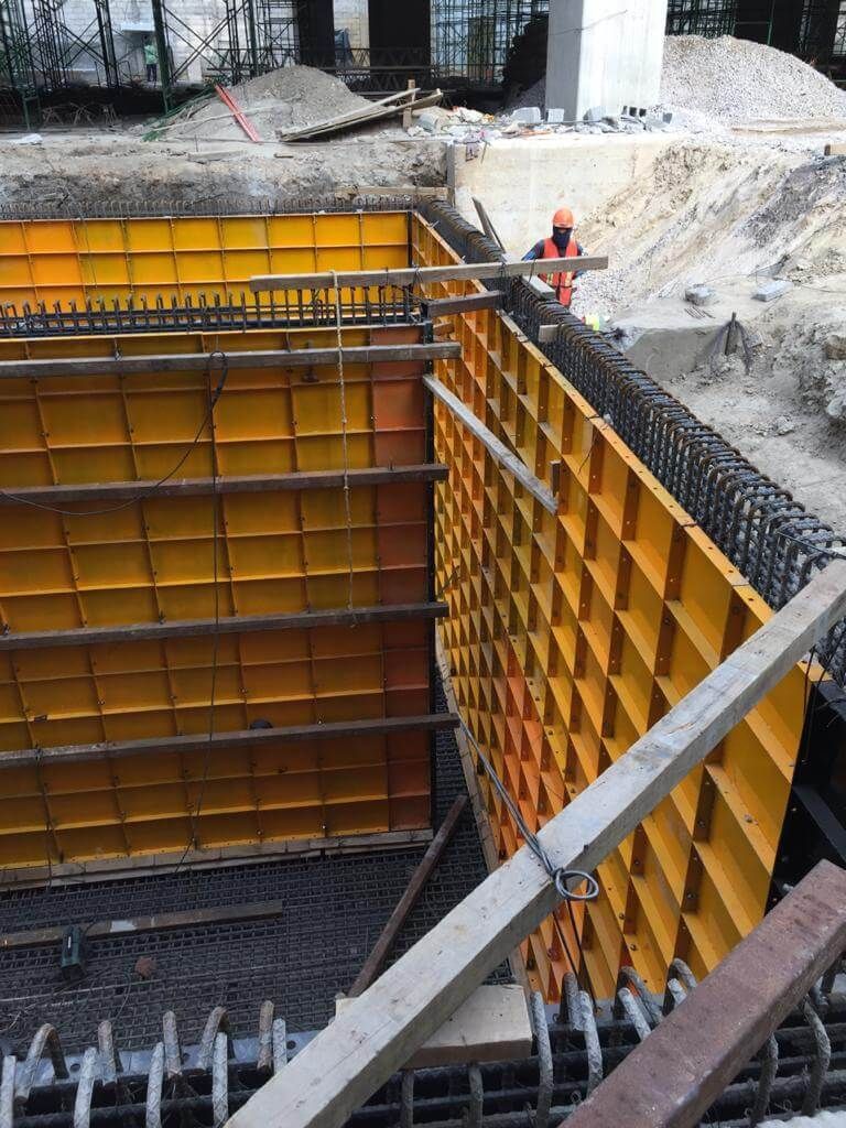 Se está construyendo una gran pared amarilla en un sitio de construcción.