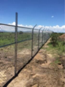 Una valla de alambre rodea un camino de tierra en un campo.