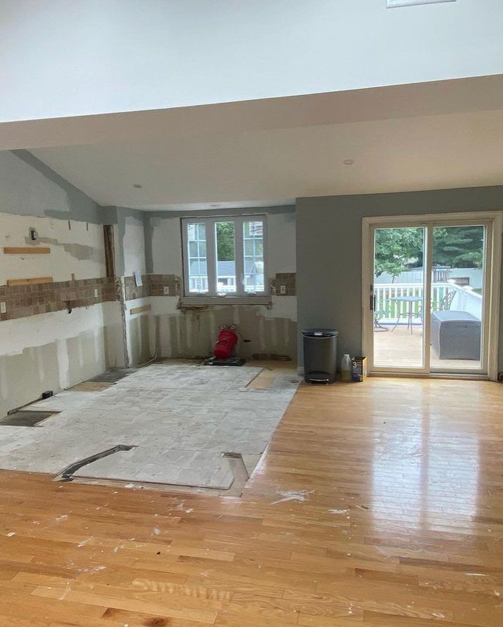 Kitchen under renovation with exposed walls, wood floors, and sliding glass door.