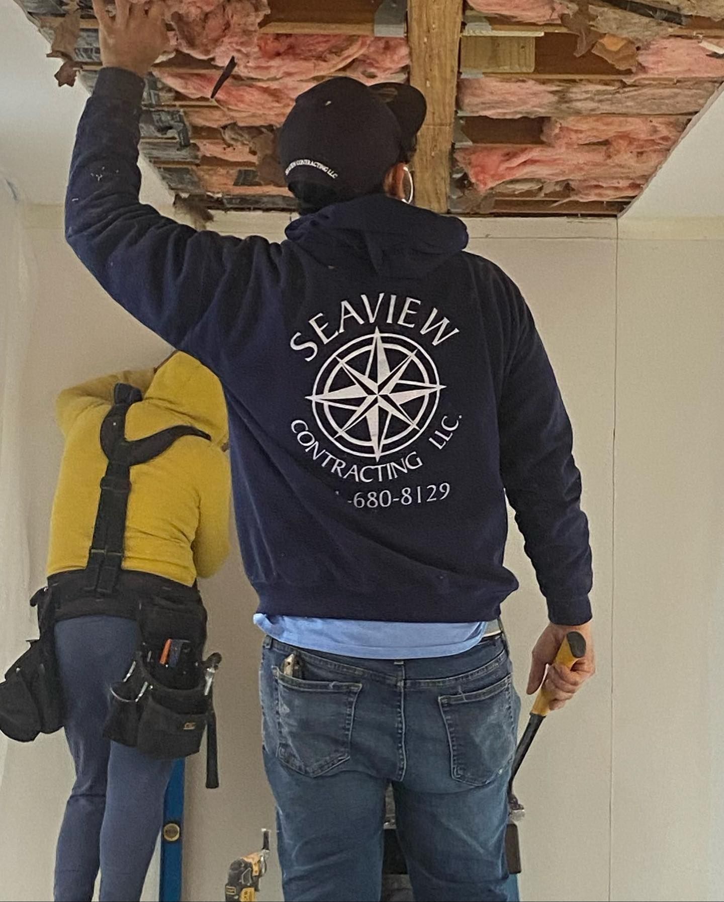 Two workers renovating a room. One in a navy sweatshirt with 