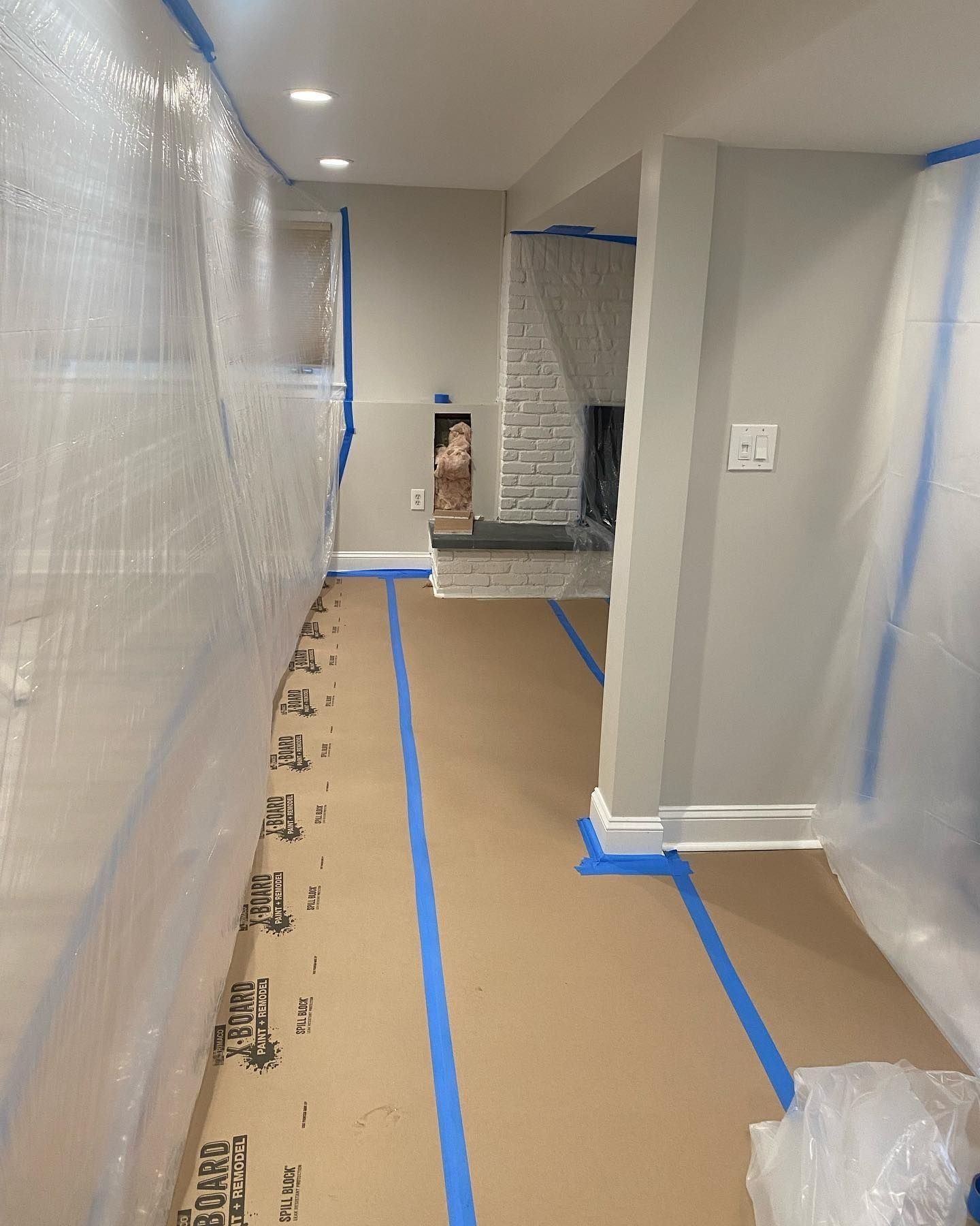 Interior renovation: Plastic sheeting and painter's tape protect hallway and flooring, grey and white walls