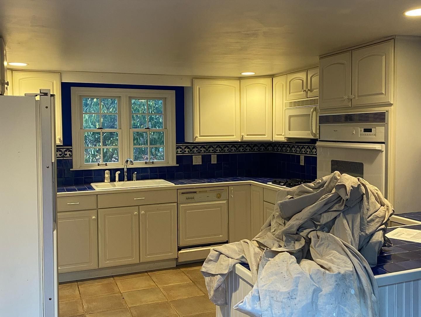 Kitchen with white cabinets, blue backsplash, and a window.