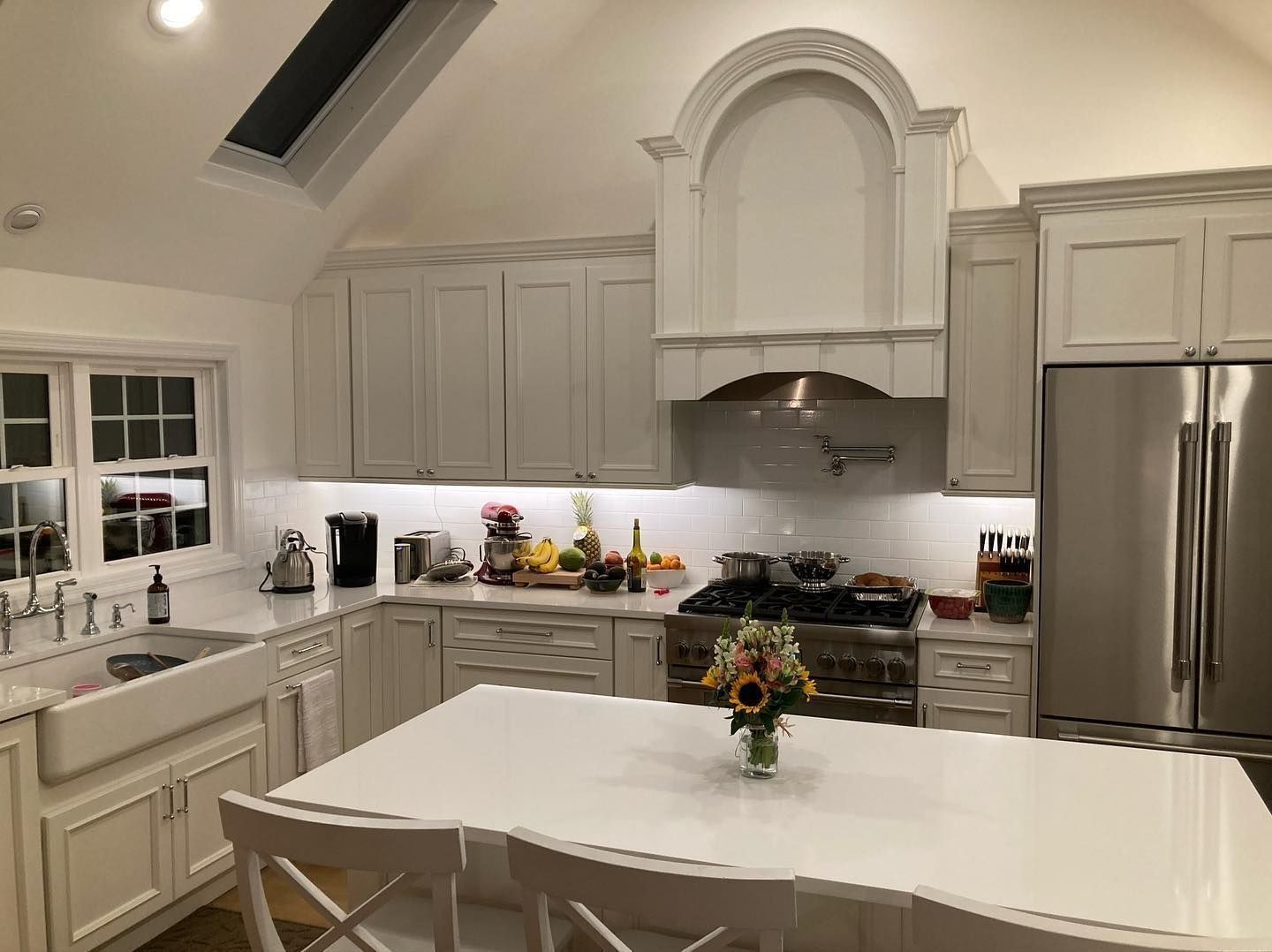 Bright white kitchen with stainless steel appliances, white cabinets, and an island.