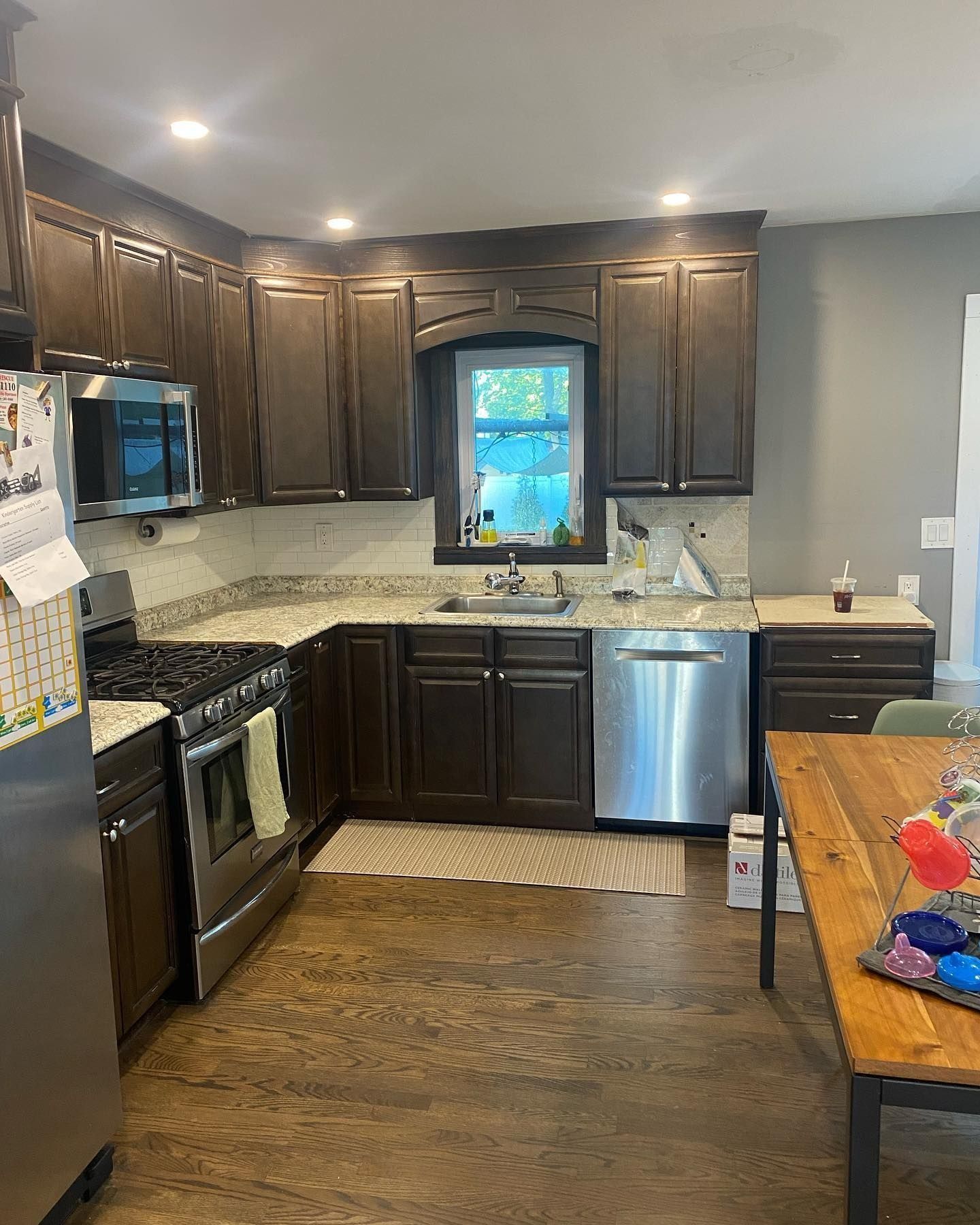 Kitchen with dark brown cabinets, stainless steel appliances, and a wooden table.